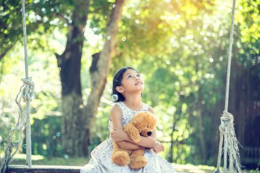 Yeşil Park 'ta oyuncak ayıya sarılırken mutlu çocuk. Oyuncak ayı, küçük çocuklar için en iyi arkadaş tatlı kız. Otizm mutlu bir şekilde oyun bahçesinde birlikte oynayarak mutlu bir aile sevgisi ve sıcacık kucaklaşmayı hisseder.