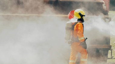 İtfaiyeci yangın hortumuyla, kimyasal köpüklü sprey motorla savaşıyor. İtfaiyeciler korunmak için kasketli, vücut korumalı üniformalı üniforma giyer. Yangın söndürücüde kurtarma eğitimi.