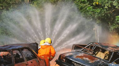 İtfaiyeci yangın hortumuyla, kimyasal köpüklü sprey motorla savaşıyor. İtfaiyeciler korunmak için kasketli, vücut korumalı üniformalı üniforma giyer. Yangın söndürücüde kurtarma eğitimi.