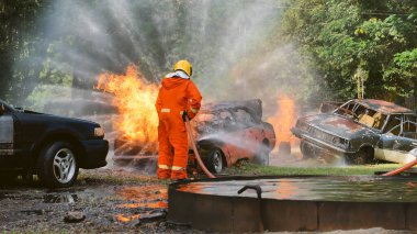 İtfaiyeci yangın hortumuyla, kimyasal köpüklü sprey motorla savaşıyor. İtfaiyeciler korunmak için kasketli, vücut korumalı üniformalı üniforma giyer. Yangın söndürücüde kurtarma eğitimi.