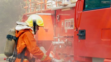 İtfaiyeci yangın hortumuyla, kimyasal köpüklü sprey motorla savaşıyor. İtfaiyeciler korunmak için kasketli, vücut korumalı üniformalı üniforma giyer. Yangın söndürücüde kurtarma eğitimi.