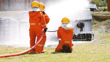 İtfaiyeci yangın hortumuyla, kimyasal köpüklü sprey motorla savaşıyor. İtfaiyeciler korunmak için kasketli, vücut korumalı üniformalı üniforma giyer. Yangın söndürücüde kurtarma eğitimi.