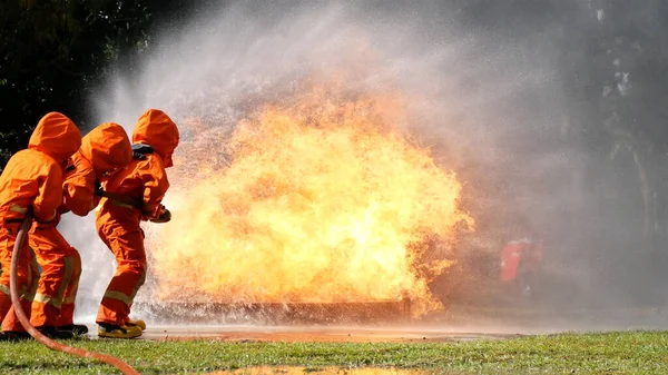 消火ホース化学水フォームスプレーエンジンを使用して炎と戦う消防士 消防士は 保護のためのハード帽子 ボディセーフスーツの制服を着用してください 消火器の救助訓練 — ストック写真