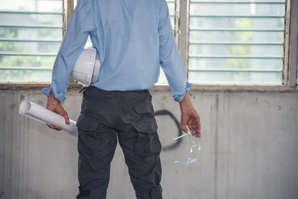 土木工学のための硬質の白い作業ヘルメットハード帽子を保持する技術者の腕の手 安全スーツの建設エンジニアの男は 建設現場で手に白い作業ヘルメットハード帽子を保持します — ストック写真
