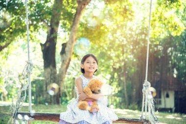 Yeşil Park 'ta oyuncak ayıya sarılırken mutlu çocuk. Oyuncak ayı, küçük çocuklar için en iyi arkadaş tatlı kız. Otizm mutlu bir şekilde oyun bahçesinde birlikte oynayarak mutlu bir aile sevgisi ve sıcacık kucaklaşmayı hisseder.