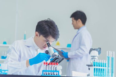 İki Asyalı bilim adamı kimya bilimi tüpü deney tüpü antikor örneğini kovid-19 virüsüne karşı laboratuvar geliştirmek için depoluyorlar. Kimya Laboratuarı 'nda bilim adamı danışmanı, analizi