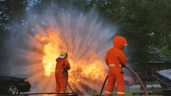 消火ホース化学水フォームスプレーエンジンを使用して炎と戦う消防士 消防士は 保護のためのハード帽子 ボディセーフスーツの制服を着用してください 消火器の救助訓練 — ストック写真