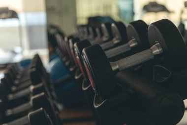 Dambıllar fiziksel halter kaldırma aletlerini rafa kaldırır. Vücut geliştiren kas geliştiren spor kulüpleri vücut egzersizleri yapıyor. Spor salonunda Black Metal dambıllar.