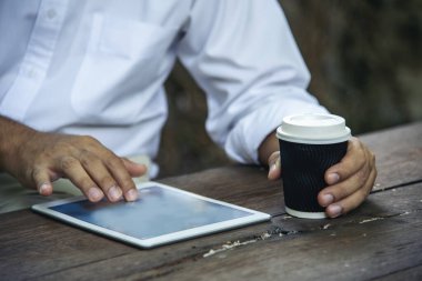 Man hands typing laptop notebook holding coffee cup outside office. Close up man hands using computer laptop sit on green park outdoors lifestyle. freelancer Men using laptop home office technology