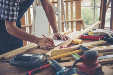 Ahşap yığını marangozluk masasında çalışan Asyalı bir zanaatkar. Mimar eller cetvel ölçü çekici ev geliştirme kullanıyor. Ahşap marangoz inşaat atölyesini tamir ediyor.