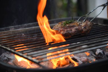 Barbekü ızgara et çubuğu ateşte, dışarıda da sıcak kömür var. Parti için domuz pastırmalı sosisli ızgara piknik. Izgara domuz eti ateşte yanıyor.
