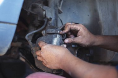 Tamirci ellerini kapayıp araba tamirhanesini tamir ediyor. Lastik değiştiriyor. Adam elleri şok emici makine araç mekanik servisini tamir ediyor. Araç bakım mühendisi.