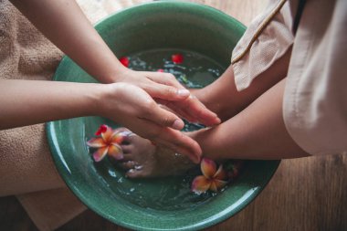 Masaj Tayland Spa ayak masajı çiçek yağı terapisi. Kadın ayak terapisi kapat. Aromaterapi salonunu rahatlat. Spa bacakları, kas gevşemesi. Mutlu kadın, rahatla cildini Ayaklarını suya batır, kaplıcaya git.