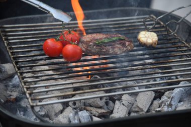 Barbekü ızgara et çubuğu ateşte, dışarıda da sıcak kömür var. Parti için domuz pastırmalı sosisli ızgara piknik. Izgara domuz eti ateşte yanıyor.