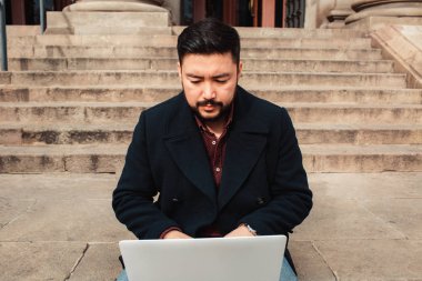 Ciddi yüz, iş veya teknoloji kavramı ile açık dizüstü bilgisayar üzerinde çalışan genç Asyalı adam