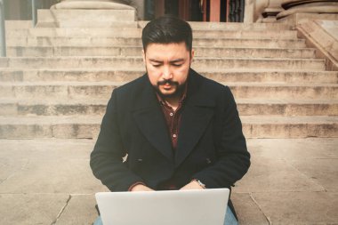 Genç Asyalı adam laptop ciddi yüz, iş veya teknoloji kavramı ile açık çalışma. Serbest çalışan.