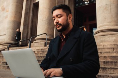 Ciddi yüz, iş veya teknoloji kavramı ile açık dizüstü bilgisayar üzerinde çalışan genç Asyalı adam