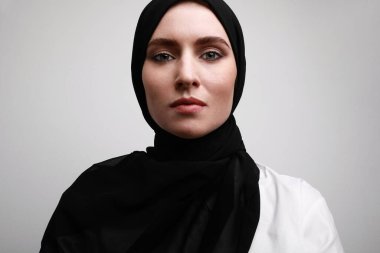 Türbanlı genç ve güzel Müslüman kadının yakın plan portresi. Beyaz duvarın üzerinde izole edilmiş..