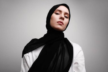Genç, tesettürlü Müslüman bir kadının portresi. Beyaz duvarın üzerinde izole edilmiş. Metin için boşluk.