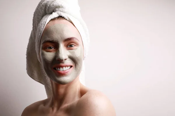 Portrét krásné mladé ženy s aplikovanou hliněnou obličejovou maskou, zábal ručník na hlavě péče o pleť koncept. — Stock fotografie