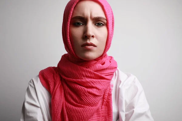 Snímek hlavy vážné mladé muslimky v fucsia hidžáb, izolované na bílém pozadí. — Stock fotografie