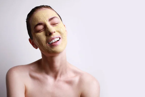 Retrato de mujer joven caucásica aplicado máscara facial con los ojos cerrados aislados sobre fondo gris. Concepto de cuidado de la piel . —  Fotos de Stock