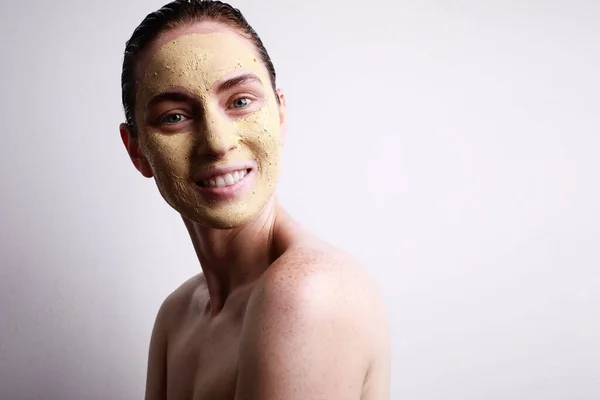 Mujer feliz con mascarilla facial hidratante con linda sonrisa aislada sobre fondo gris. Belleza y cuidado de la piel . —  Fotos de Stock