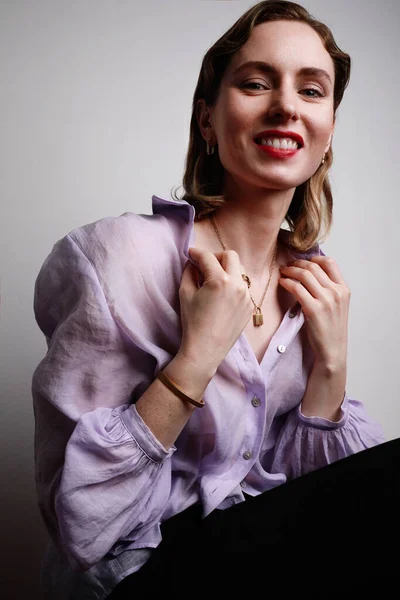 Atraktivní žena modelka na sobě fialové tričko s úsměvem a pózování na bílém pozadí. — Stock fotografie