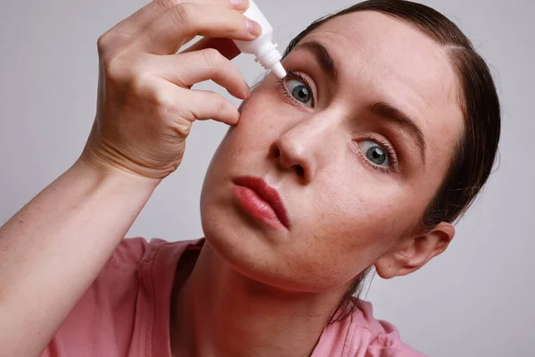 Tiro na cabeça de uma mulher com um olho ferido a inserir colírio. Conceito de cuidados de saúde e visão. Conjuctivitis. Espaço para o espaço . — Fotografia de Stock