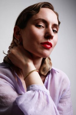 Mor gömlek giyen, sarı saçlı güzel bir kadının dikey yakın çekimi. Sevimli bir gülümsemeyle kameraya bakıyorum..