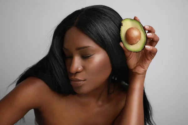 Retrato da cabeça de uma jovem negra segurando uma fatia de abacate. Modo de vida saudável . — Fotografia de Stock