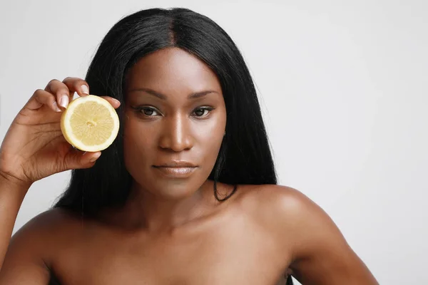 Headshot de bela pele escura modelo feminino segurando fatia de citrinos vitamina c fruta fundo marrom isolado . — Fotografia de Stock