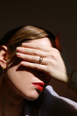 Güzellik mankeni yüzüne dokunuyor altın yüzük takıyor. Yaratıcı bir imaj. Mücevher konsepti.