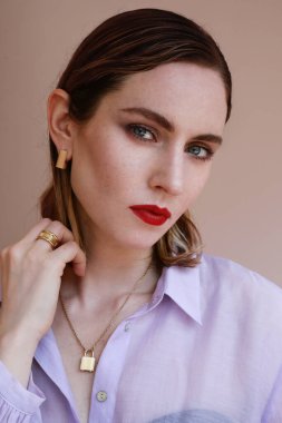 Altın mücevherleri olan çekici bir kadının kameraya bakarken dikey portresi. Mücevher ve lüks konsept.