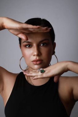 Bronz tenli genç bir kadının dikey portresi. Renkli arka planda bir sürü yüzük var..