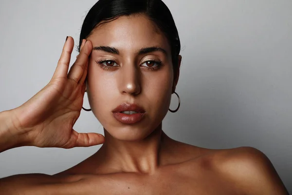 Retrato de cerca de una joven de piel marrón muestra orgullosamente su piel mientras posa sobre un fondo blanco . —  Fotos de Stock