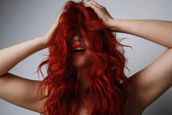 Cabeleireiro conceito estúdio tiro. Retrato de ruiva atraente mulher posando sobre fundo cinza . — Fotografia de Stock