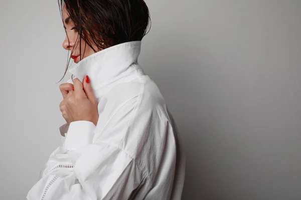 Portrait latéral d'une femme confiante portant une chemise blanche posant sur un fond gris. — Photo