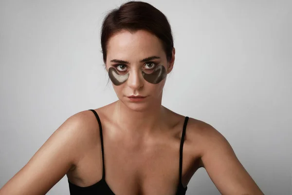 Portrait de belle jeune femme utilisant des patchs cosmétiques yeux santé peau femme beauté. Gros plan. — Photo