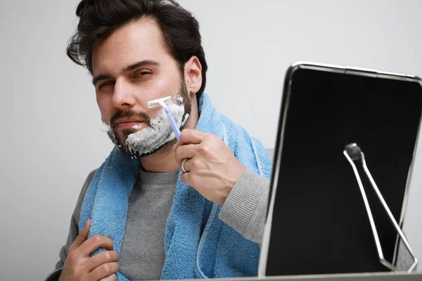 Bonito barbudo homem em roupas casuais iwith barba aplicar espuma de barbear posando no fundo cinza , — Fotografia de Stock