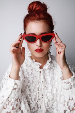 Kafkasyalı genç, sağlıklı bir kadının dikey portresi. Gözlüklü ve kameraya bakıyor. Beyaz arkaplanda izole.