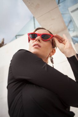 Kırmızı güneş gözlüğü takan mutlu ve neşeli olgun bir kadının dikey portresi.. 