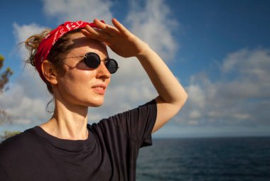 Yazın gün batımında sahilde oturan genç bir kadın..