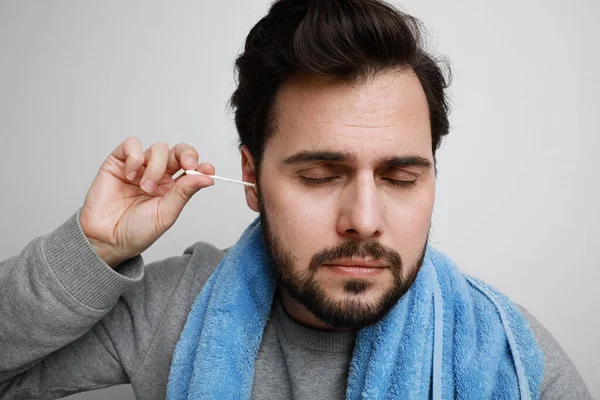 Retrato de perto do homem barbudo limpando as orelhas isolado com os olhos fechados. Espaço para texto. — Fotografia de Stock