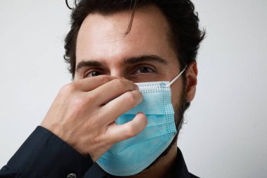 Sağlık maskesi takan adam. Genç adam arka planda duruyor ve yana bakıyor. Metin için boş alan.