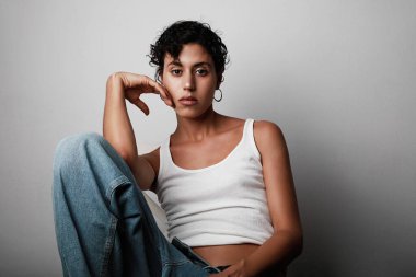 Genç bir kadın bir sandalyede oturmuş, boş alana bakıyor ve izole edilmiş beyaz afiş arka planına bakıyor.