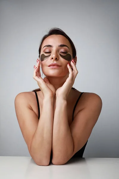 Retrato vertical de mujer joven optimista cuidar de la piel debajo de los ojos. Concepto de cuidado de la piel. Espacio para texto. —  Fotos de Stock
