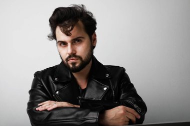 Beyaz arka planda poz veren deri ceketli yakışıklı motorcu. Metin için boşluk.