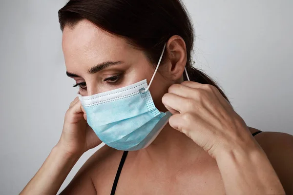 Close-up of young caucasian brunette woman using medical mask. Stay home. Pandemic situation. — Stock Photo, Image