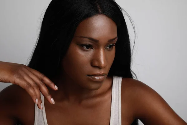 Close-up da jovem mulher negra, com a pele perfeita, olhando para o lado. Posando sobre fundo branco. — Fotografia de Stock